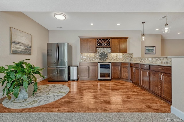 kitchen with tasteful backsplash, light countertops, freestanding refrigerator, beverage cooler, and a peninsula