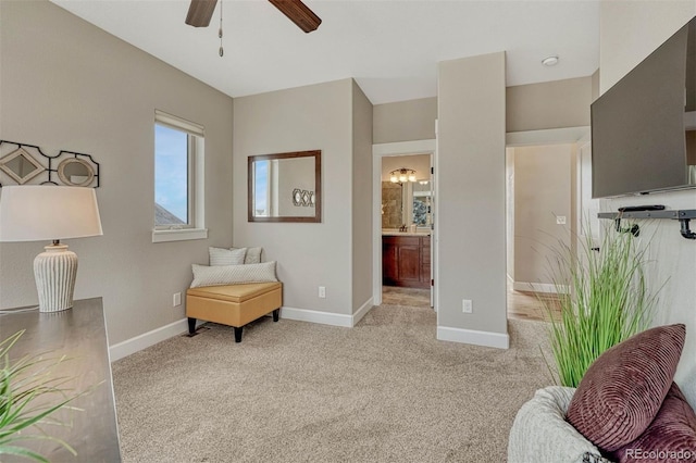 living area with ceiling fan, baseboards, and light colored carpet