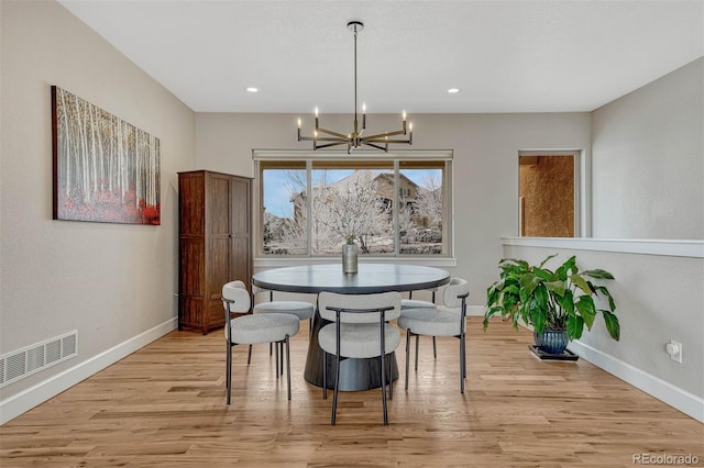 dining area featuring light wood finished floors, baseboards, visible vents, and an inviting chandelier