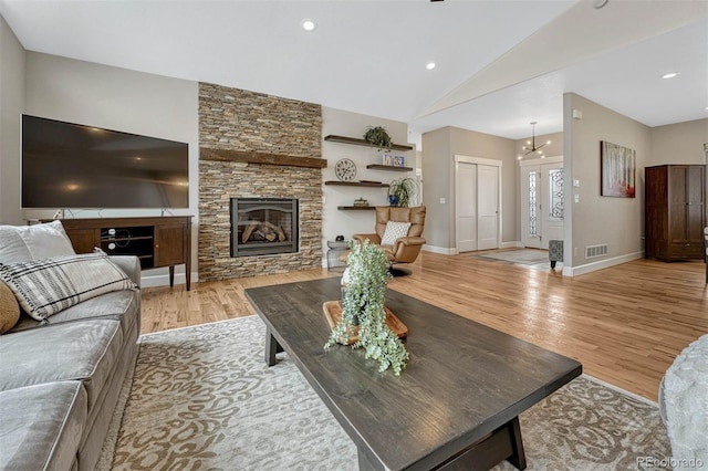 living room with light wood finished floors, baseboards, visible vents, vaulted ceiling, and a fireplace