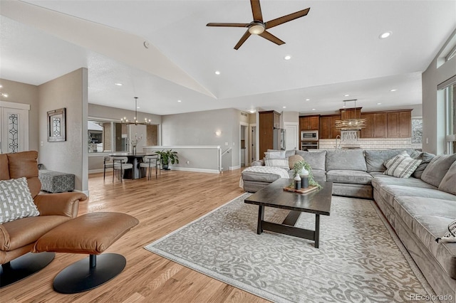 living area with lofted ceiling, light wood-style flooring, recessed lighting, ceiling fan with notable chandelier, and baseboards