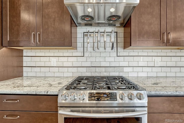 kitchen with tasteful backsplash, stainless steel range with gas cooktop, light stone countertops, and exhaust hood