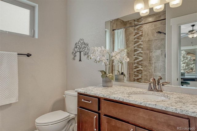 bathroom with toilet, a ceiling fan, tiled shower, and vanity