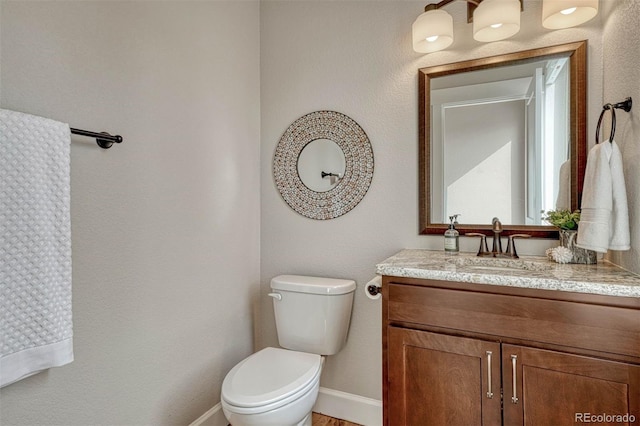 bathroom with baseboards, vanity, and toilet