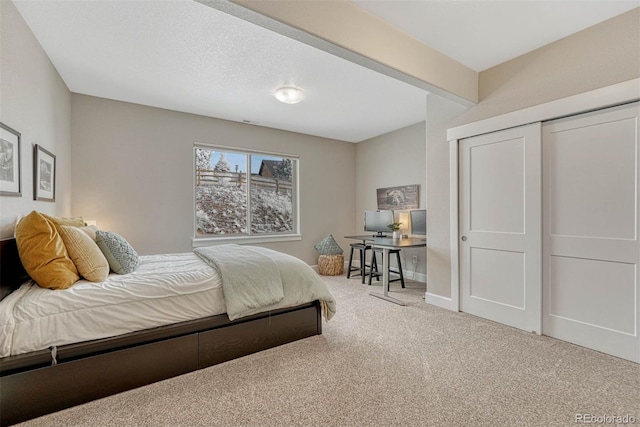 carpeted bedroom with a closet, a textured ceiling, and baseboards