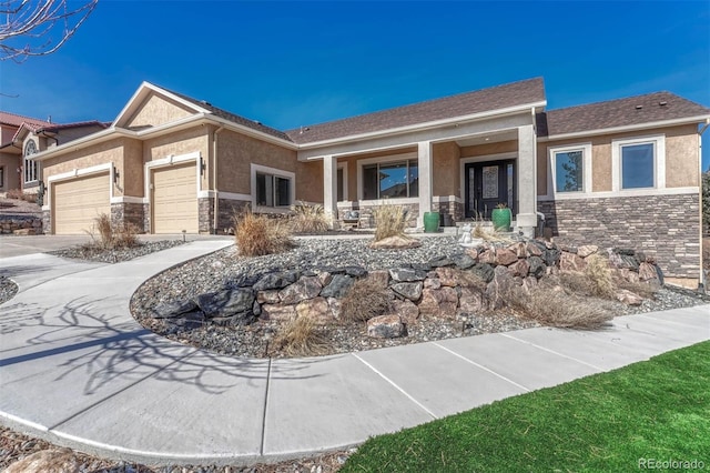 view of front of property featuring a porch, an attached garage, stone siding, driveway, and stucco siding