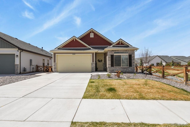 craftsman-style house featuring a front lawn, stone siding, concrete driveway, fence, and an attached garage