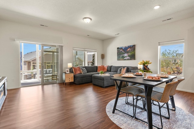 living area with visible vents, a textured ceiling, and dark wood-style floors
