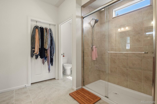 bathroom with toilet, baseboards, and a stall shower