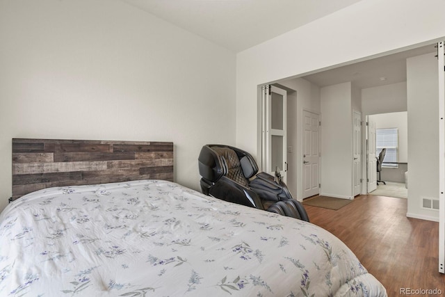 bedroom featuring visible vents, baseboards, and wood finished floors