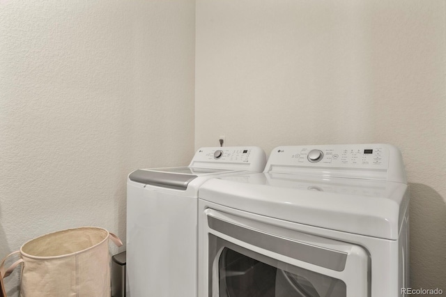 washroom featuring a textured wall, washer and dryer, and laundry area