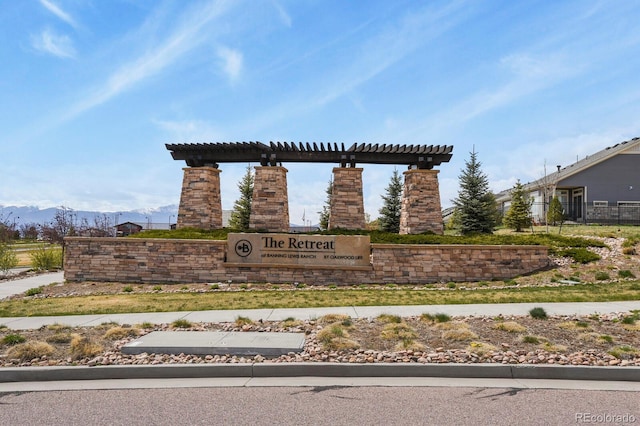 community / neighborhood sign with fence and a mountain view