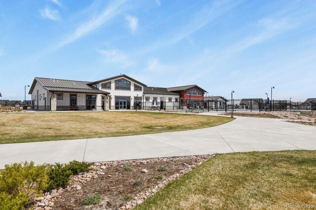 modern farmhouse with a front lawn, board and batten siding, fence, metal roof, and a standing seam roof