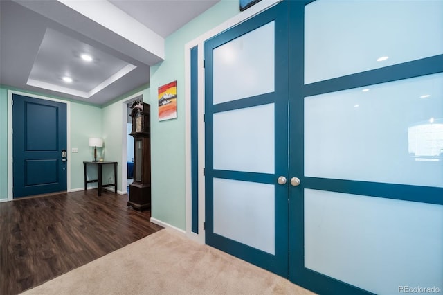 corridor with a raised ceiling, dark hardwood / wood-style floors, and french doors