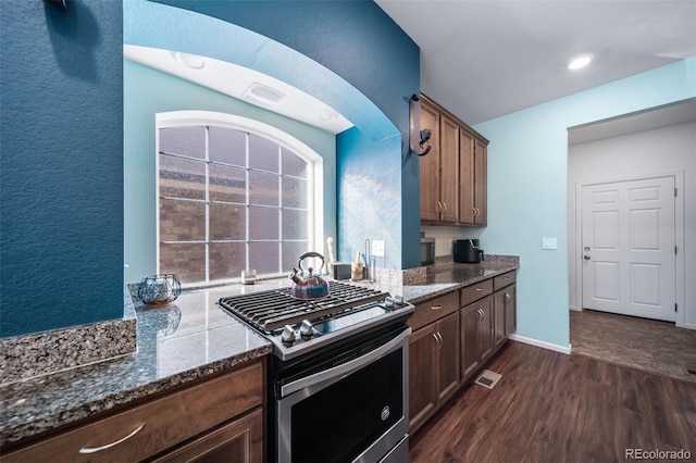 kitchen with dark stone countertops, stainless steel gas range, and dark hardwood / wood-style flooring