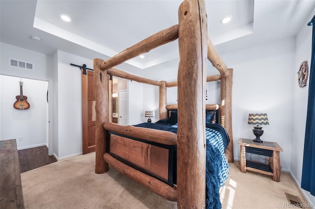 carpeted bedroom with beamed ceiling and a barn door