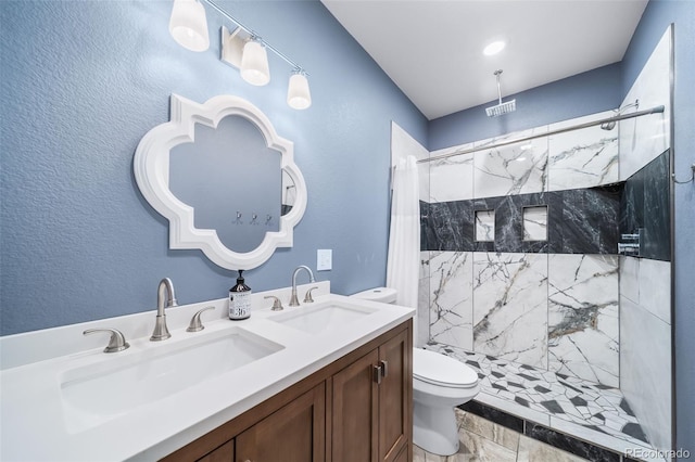 bathroom featuring a tile shower, vanity, and toilet