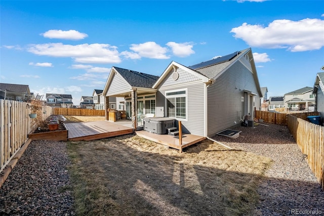 back of property featuring a wooden deck, central AC, a hot tub, and solar panels