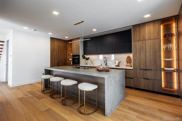 kitchen with a breakfast bar area, a large island, sink, and light hardwood / wood-style floors