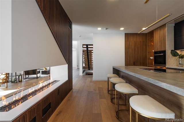 bar featuring light wood-type flooring and black appliances