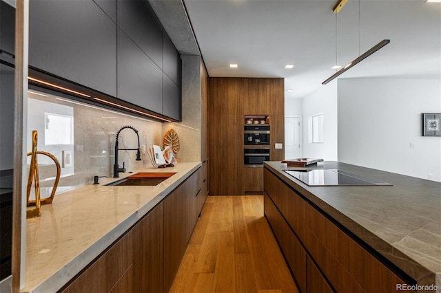 kitchen featuring sink, light hardwood / wood-style flooring, stainless steel double oven, black electric stovetop, and backsplash