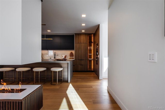 bar featuring decorative backsplash and light wood-type flooring