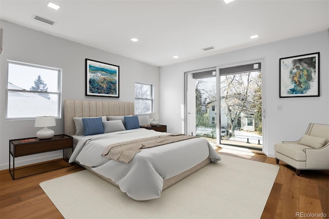 bedroom featuring multiple windows, access to exterior, and wood-type flooring