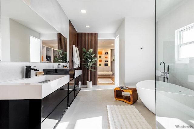 bathroom with vanity, a bathtub, and concrete floors