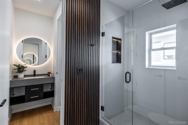 bathroom featuring hardwood / wood-style flooring, vanity, and a shower with shower door