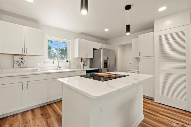 871 S Worchester St, Aurora, CO 80012 - kitchen with stainless steel fridge with ice dispenser, black electric stovetop, a center island, white cabinetry, and light wood-style flooring