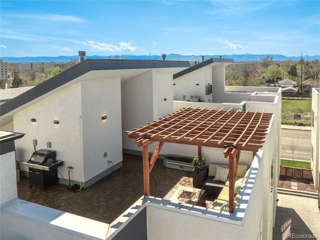 view of side of home featuring a pergola, stucco siding, a patio area, and a mountain view