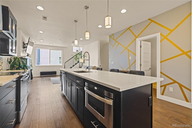 kitchen with light countertops, visible vents, appliances with stainless steel finishes, a sink, and dark cabinets
