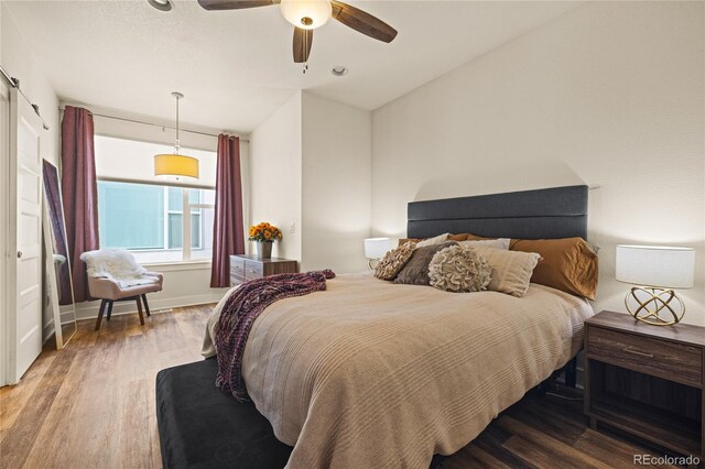 bedroom with a ceiling fan, baseboards, and wood finished floors