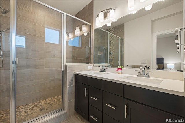 full bath featuring a stall shower, double vanity, and a sink