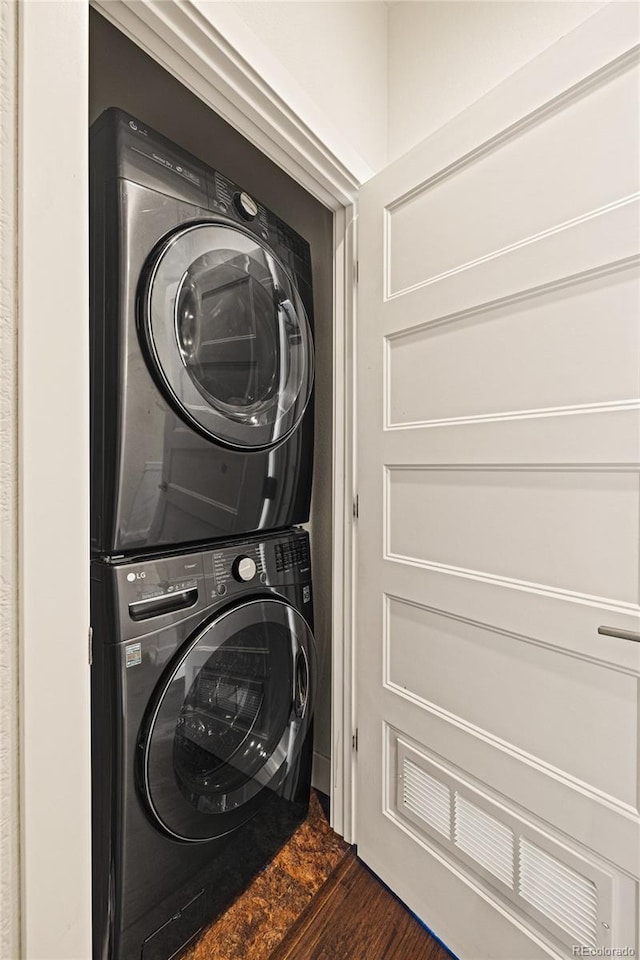 laundry room with dark wood-style floors, stacked washer / dryer, and laundry area