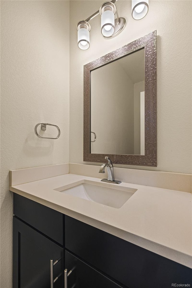 bathroom with a textured wall and vanity