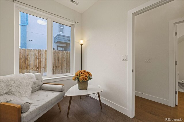 sitting room with baseboards, visible vents, vaulted ceiling, and wood finished floors