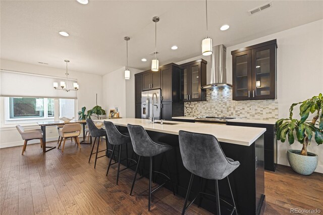 1336 Sheridan Blvd Unit 108, Denver, CO 80214 - kitchen with wall chimney range hood, a sink, light countertops, a kitchen breakfast bar, and a center island with sink