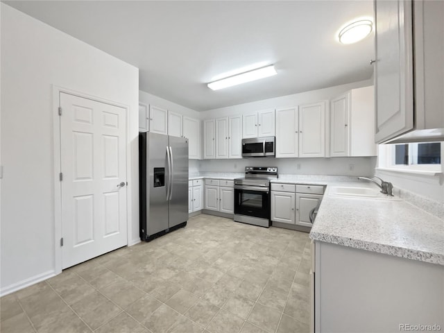 kitchen with appliances with stainless steel finishes, white cabinets, and a sink