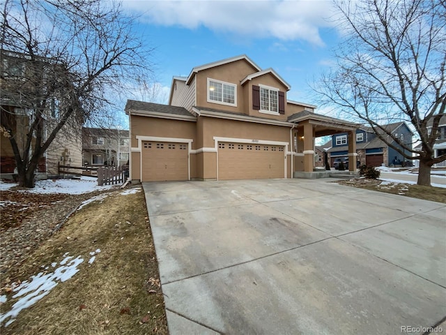 view of front of property featuring a garage, driveway, fence, and stucco siding