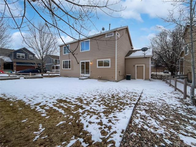 snow covered back of property featuring entry steps and fence