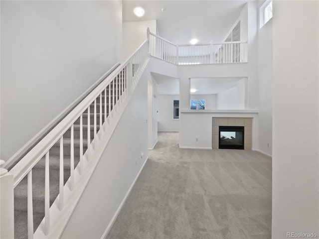 interior space with a high ceiling, carpet, a fireplace, and baseboards