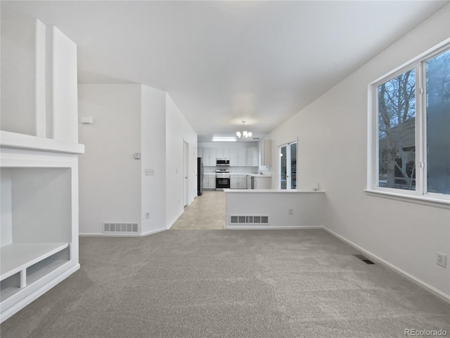 unfurnished living room featuring visible vents, a notable chandelier, light carpet, and baseboards