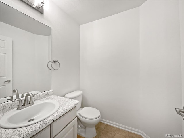 half bathroom featuring baseboards, vanity, toilet, and tile patterned floors