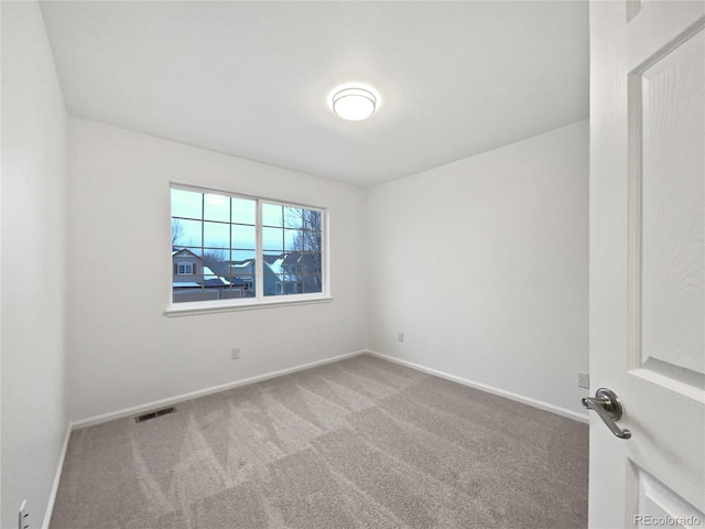 spare room with carpet, visible vents, and baseboards