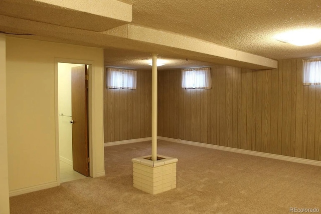 finished basement featuring carpet, wooden walls, and a textured ceiling