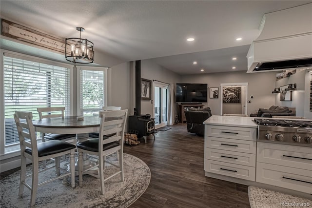 dining room with an inviting chandelier, a wood stove, and dark hardwood / wood-style floors