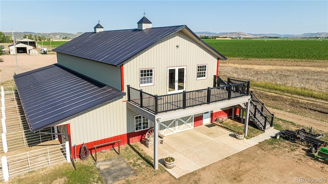 back of property with a rural view, a patio area, french doors, a garage, and a mountain view