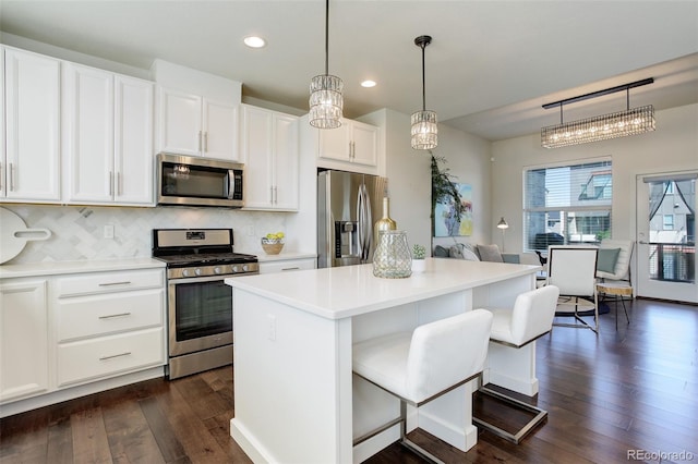 9180 E 52nd Dr, Denver, CO 80238 - kitchen with appliances with stainless steel finishes, dark wood-style flooring, a center island, recessed lighting, and tasteful backsplash