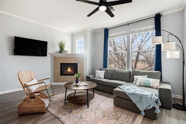 living room featuring a tiled fireplace, ceiling fan, crown molding, and hardwood / wood-style flooring